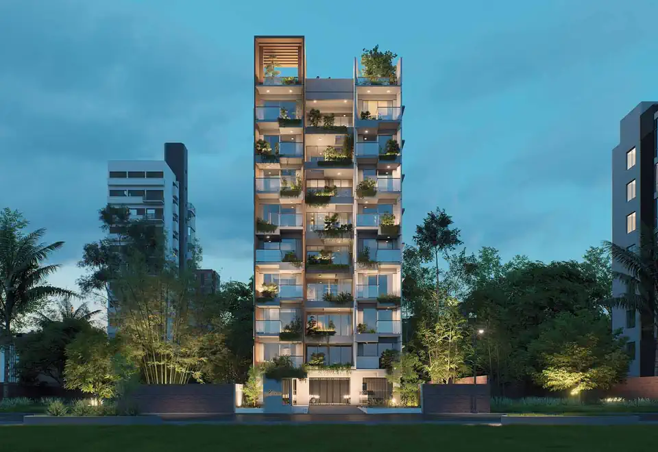 A residential building at dusk, lit from within, standing among mature trees