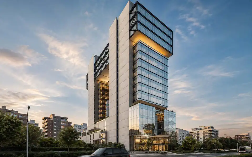 A finished tower at dusk seen from the road, its lower floors glazed and lit